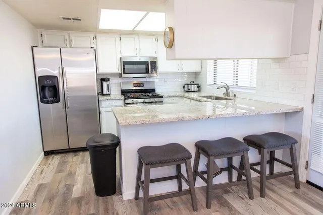 a kitchen with stainless steel appliances a dining table chairs refrigerator and microwave