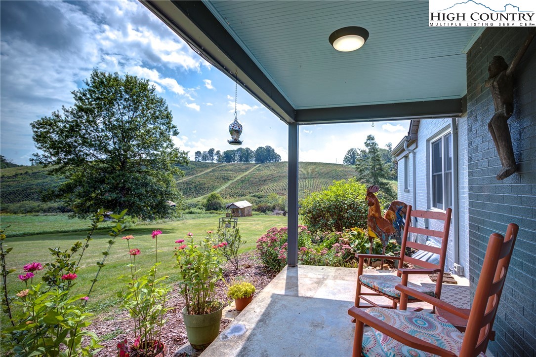 1046 J E Gentry Road Laurel Springs, NC 28644 - Photo 11 of 49 a porch with a table and chairs and potted plants