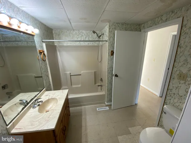 a bathroom with a sink a toilet a mirror and shower