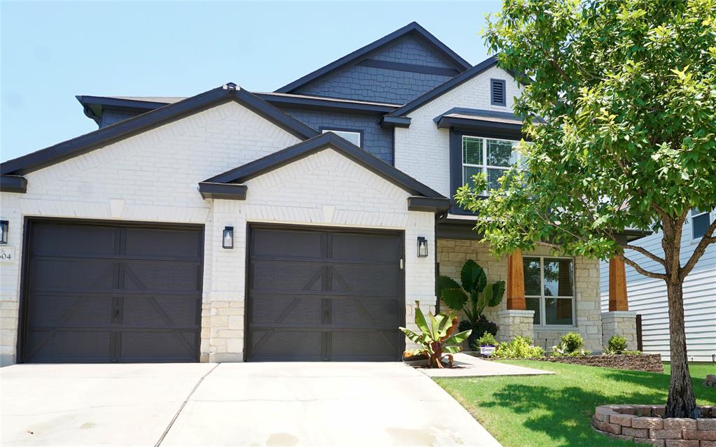 Welcome to 8604 Capitol View Dr! Craftsman inspired home with a garage, stone siding, concrete driveway, and a front lawn