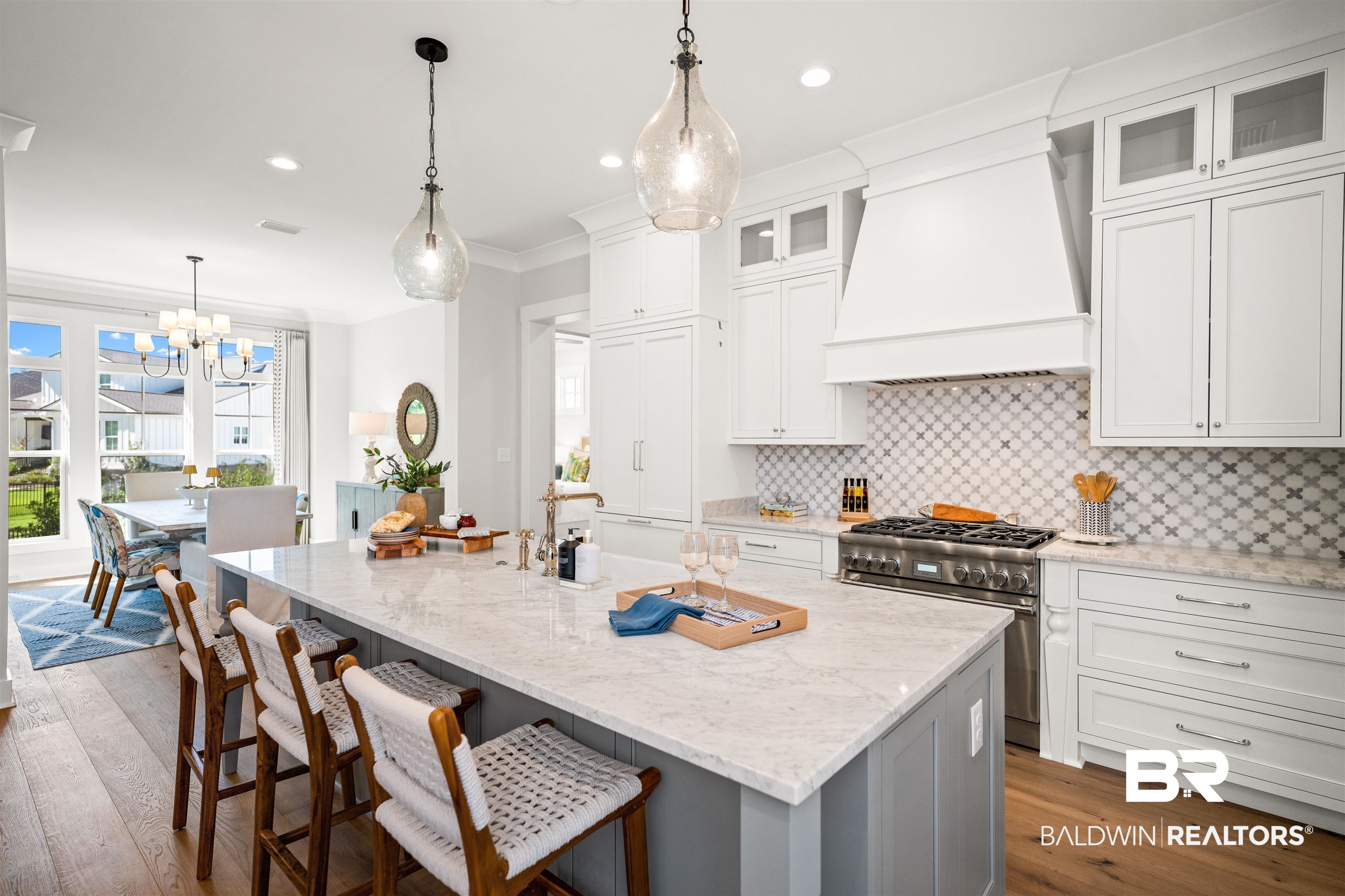 156 Hyacinth Street Fairhope, AL 36532 - Photo 12 of 61 Kitchen featuring pendant lighting, white cabinetry, light stone countertops, hardwood / wood-style flooring, and glass insert cabinets