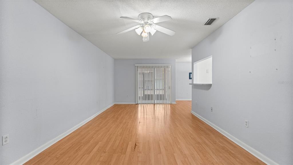 501 Southwest 75th Street, Unit B5 Gainesville, FL 32607 - Photo 5 of 38 a view of an empty room with chandelier fan and wooden floor