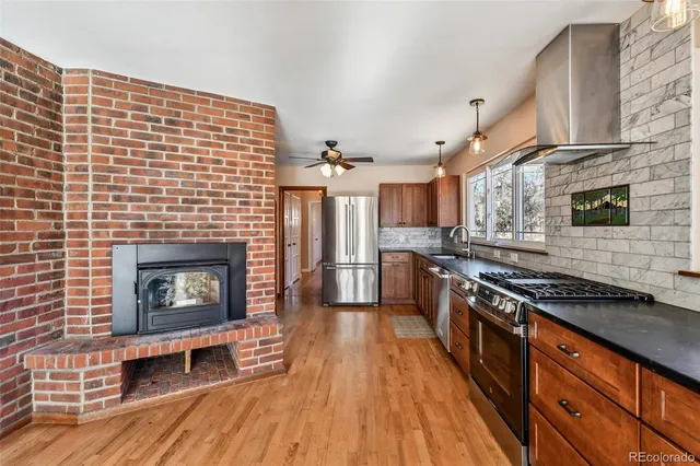 a kitchen with stainless steel appliances wooden floor and a fireplace