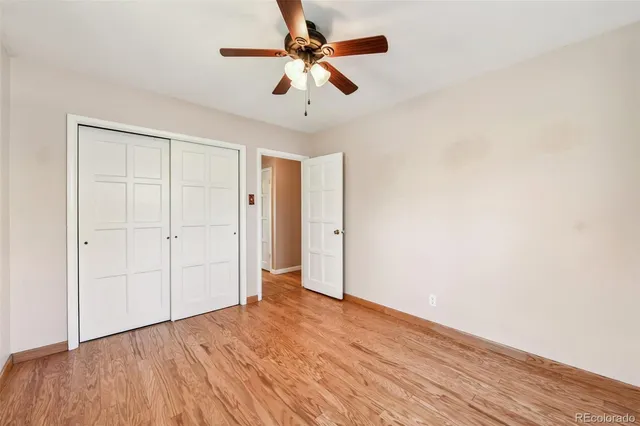 an empty room with wooden floor ceiling fan and windows