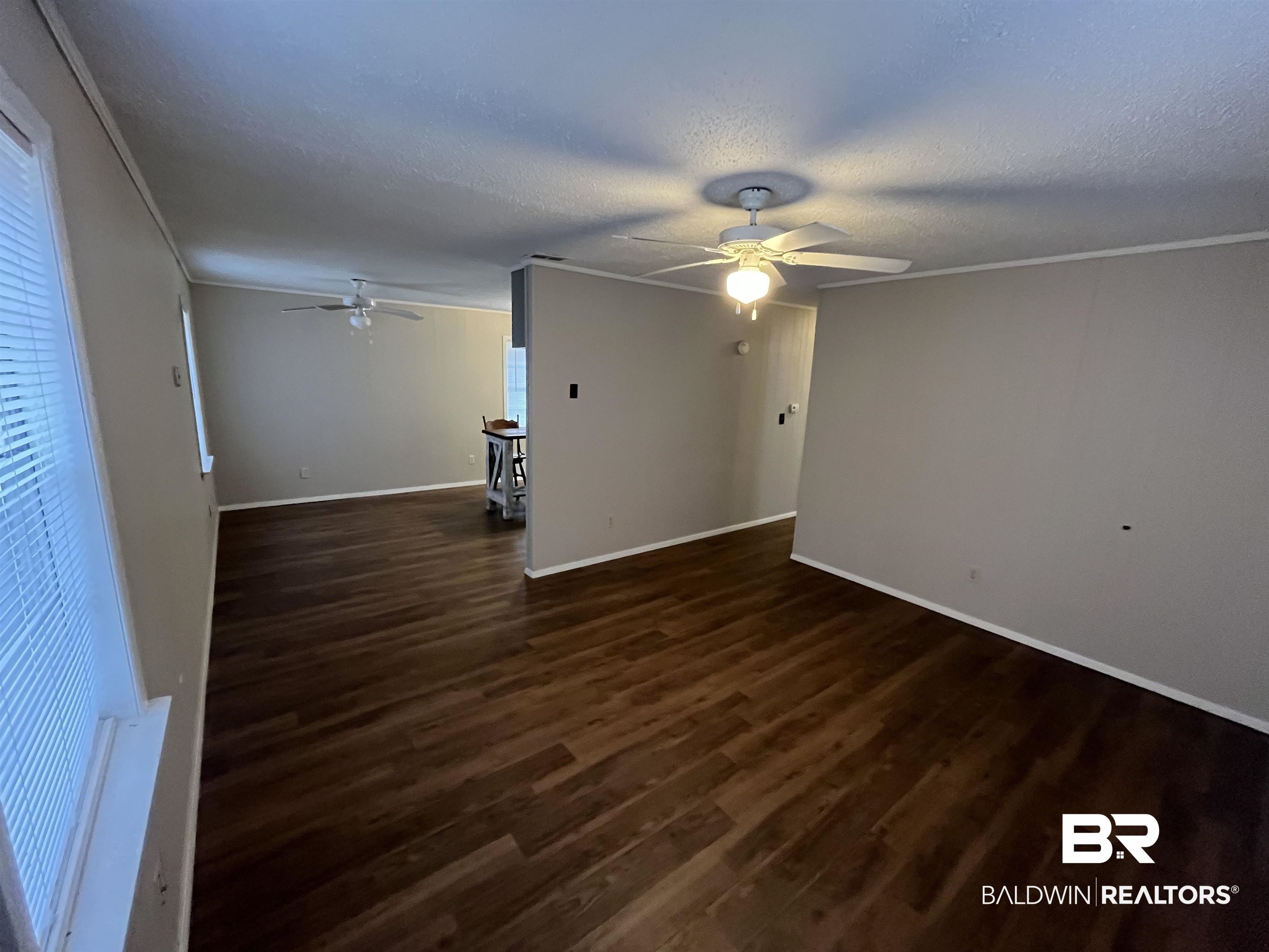 103 Roadway Street Brewton, AL 36426 - Photo 6 of 13 Unfurnished living room with ceiling fan, dark wood-type flooring, a textured ceiling, and ornamental molding