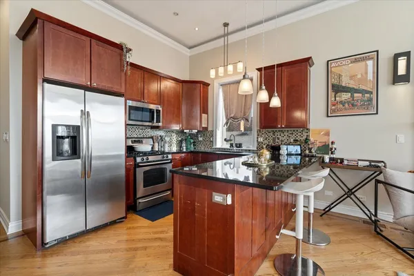a kitchen with stainless steel appliances granite countertop a refrigerator a stove and a sink with wooden floor