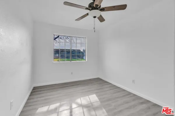an empty room with a window and a fan