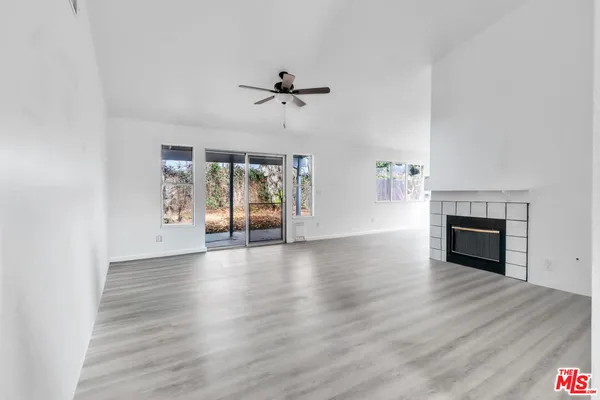an empty room with wooden floor fireplace and windows
