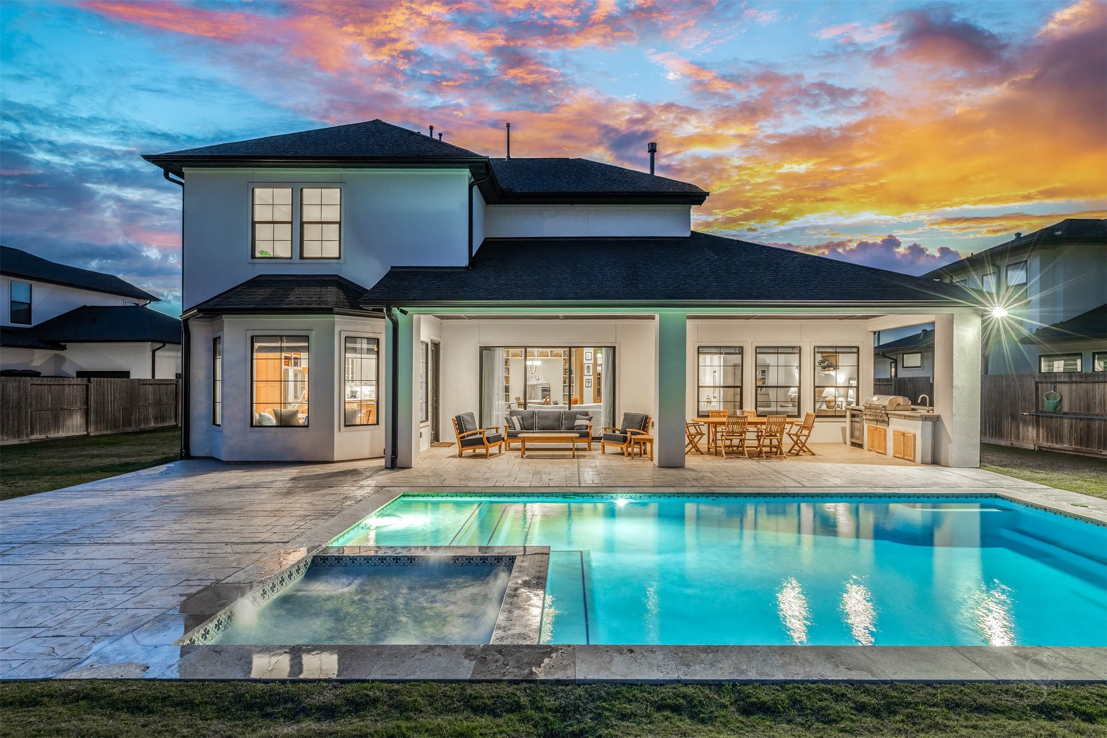 27919 Indigo Ridge Drive Fulshear, TX 77441 - Photo 42 of 50 The resort-style backyard showcases a shimmering pool and spa surrounded by expansive stone decking, creating an exquisite setting for both relaxation and entertaining. An impressive extended covered patio with outdoor kitchen elevates the experience, offering a sophisticated space for alfresco dining and luxurious year-round outdoor living.