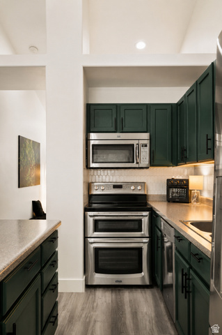 204 Lyman Lane Bountiful, UT 84010 - Photo 7 of 28 Kitchen featuring dark green cabinetry with matte black hardware, stainless steel appliances, light wood-finish flooring, and light-toned countertops