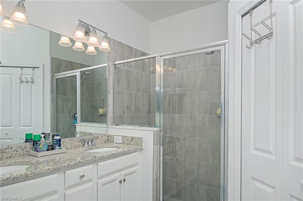 2073 Tamarron Lane Naples, FL 34120 - Photo 11 of 22 a bathroom with a granite countertop sink a mirror and a shower