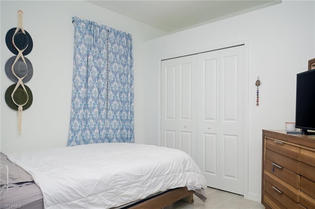2073 Tamarron Lane Naples, FL 34120 - Photo 12 of 22 a bedroom with a bed and a flat tv screen on the dresser