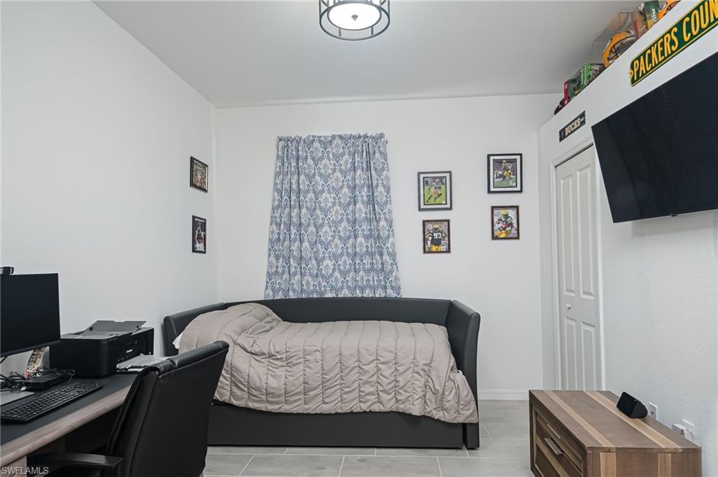 2073 Tamarron Lane Naples, FL 34120 - Photo 13 of 22 a bedroom with a bed and a flat screen tv