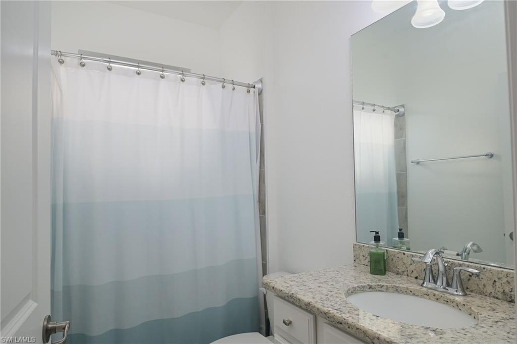 2073 Tamarron Lane Naples, FL 34120 - Photo 14 of 22 a bathroom with a granite countertop sink toilet and shower
