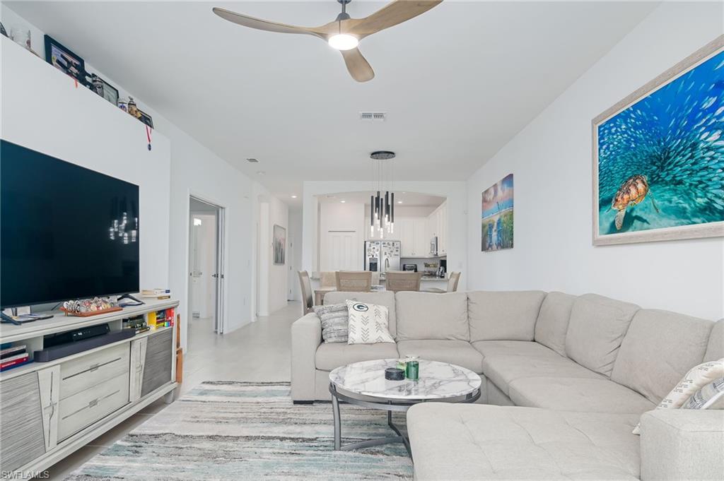 2073 Tamarron Lane Naples, FL 34120 - Photo 4 of 22 a living room with furniture a flat screen tv and kitchen view