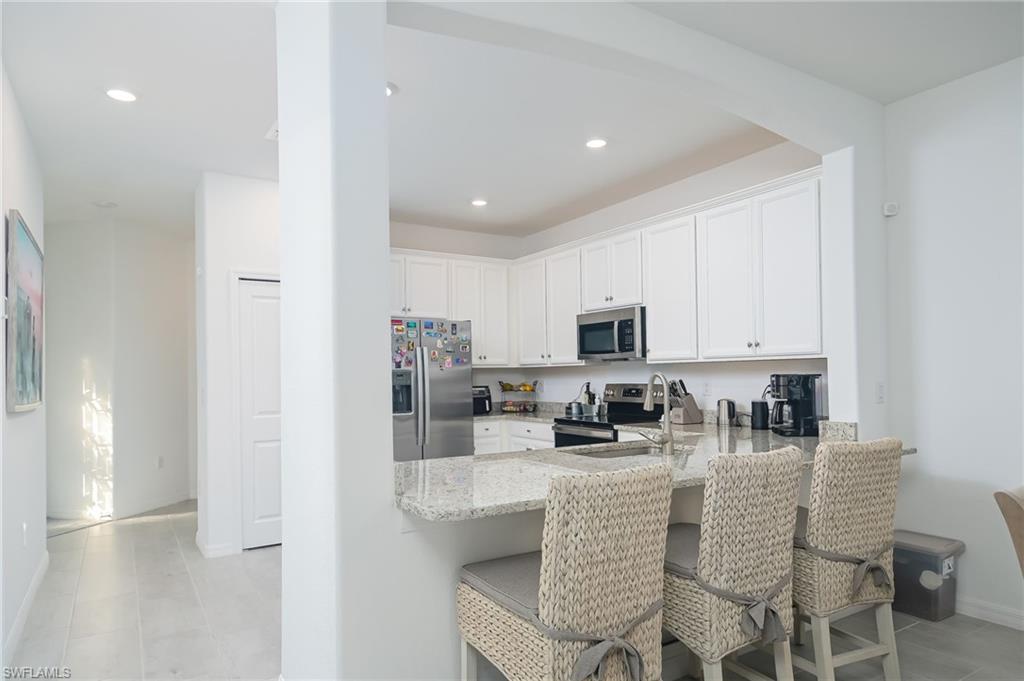 2073 Tamarron Lane Naples, FL 34120 - Photo 6 of 22 a kitchen with stainless steel appliances granite countertop a refrigerator a stove a sink a white table and chairs
