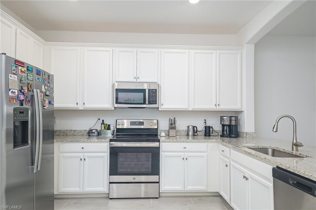 2073 Tamarron Lane Naples, FL 34120 - Photo 8 of 22 a kitchen with white cabinets sink and stainless steel appliances