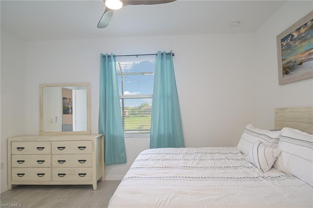 2073 Tamarron Lane Naples, FL 34120 - Photo 10 of 22 a bedroom with a bed and a chandelier