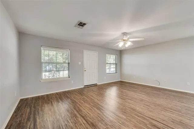 a view of an empty room with a window and wooden floor