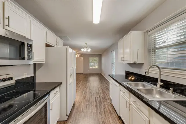 a kitchen with granite countertop a sink dishwasher stove and microwave with wooden floor