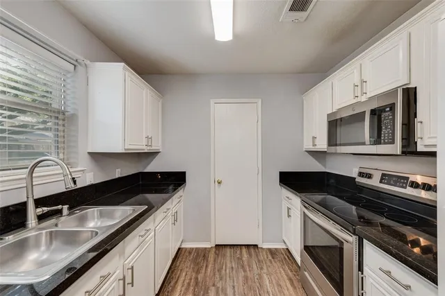 a view of a hallway with wooden floor and a kitchen