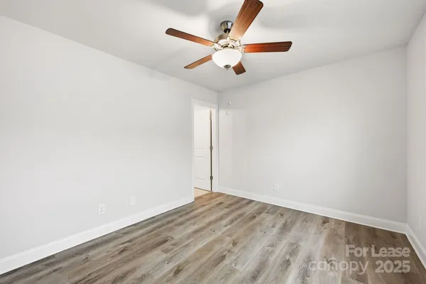 an empty room with wooden floor and ceiling fan