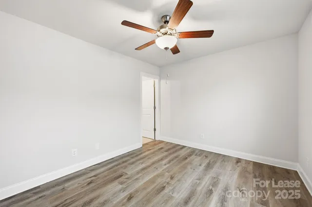 an empty room with wooden floor and ceiling fan
