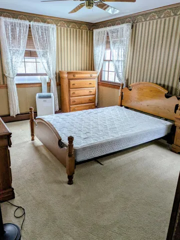 a bedroom with a bed and large window with chair