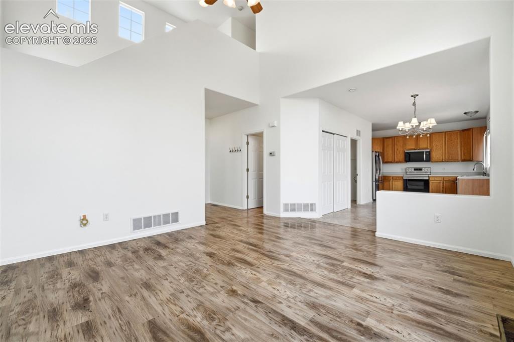 7904 Coffee Road Peyton, CO 80831 - Photo 5 of 48 Spacious living area featuring high ceilings, upper-level windows, and wood-finish flooring