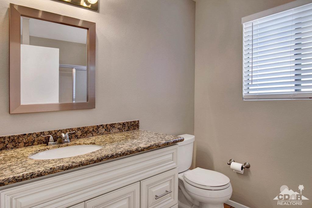 34041 Emily Way Rancho Mirage, CA 92270 - Photo 16 of 25 a bathroom with a granite countertop sink a toilet and mirror