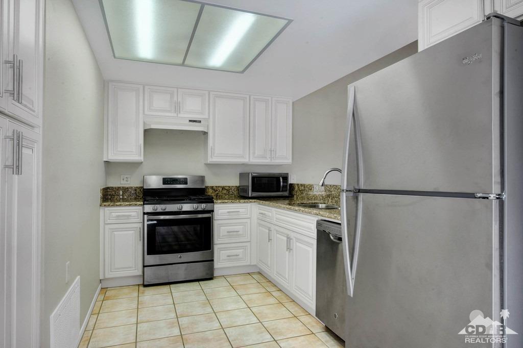 34041 Emily Way Rancho Mirage, CA 92270 - Photo 7 of 25 a kitchen with a stove a refrigerator and white cabinets