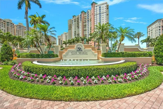 a view of a fountain in front of a big yard with flower plants