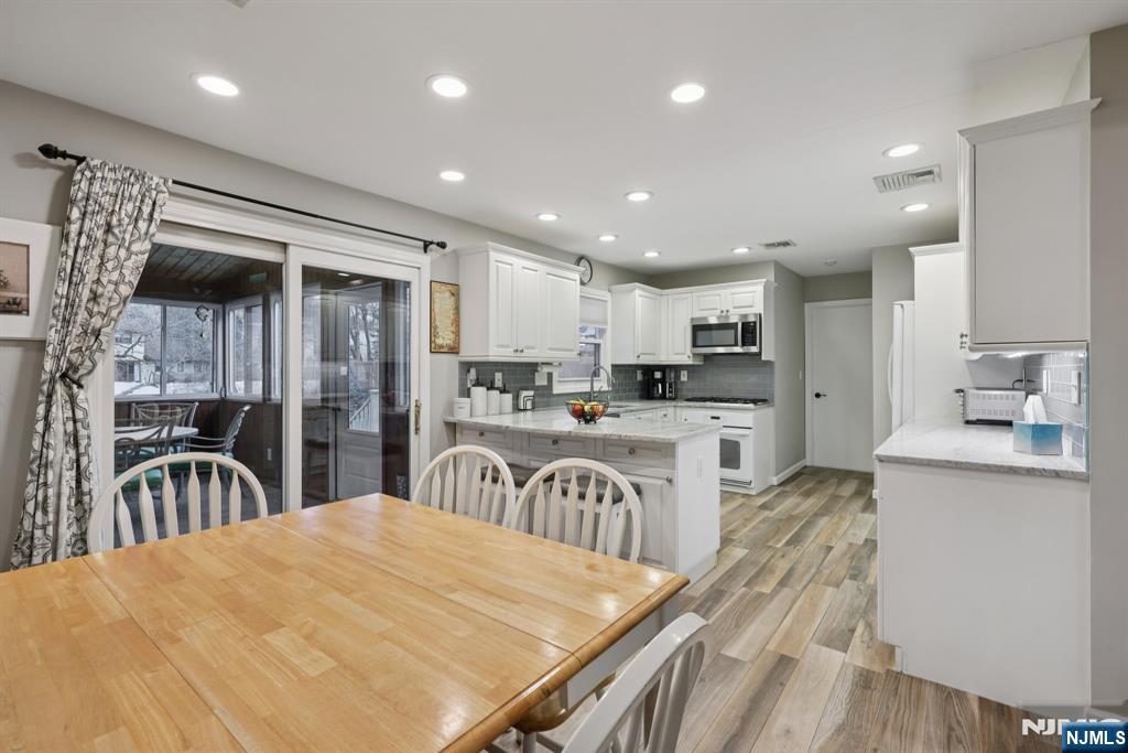 7 Welsh Court Wayne, NJ 07470 - Photo 14 of 40 a kitchen with stainless steel appliances kitchen island granite countertop a refrigerator oven a sink a dining table and chairs with wooden floor