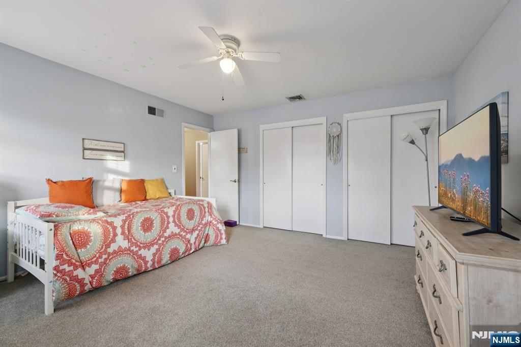 7 Welsh Court Wayne, NJ 07470 - Photo 25 of 40 a bedroom with a bed flat screen tv and a chandelier