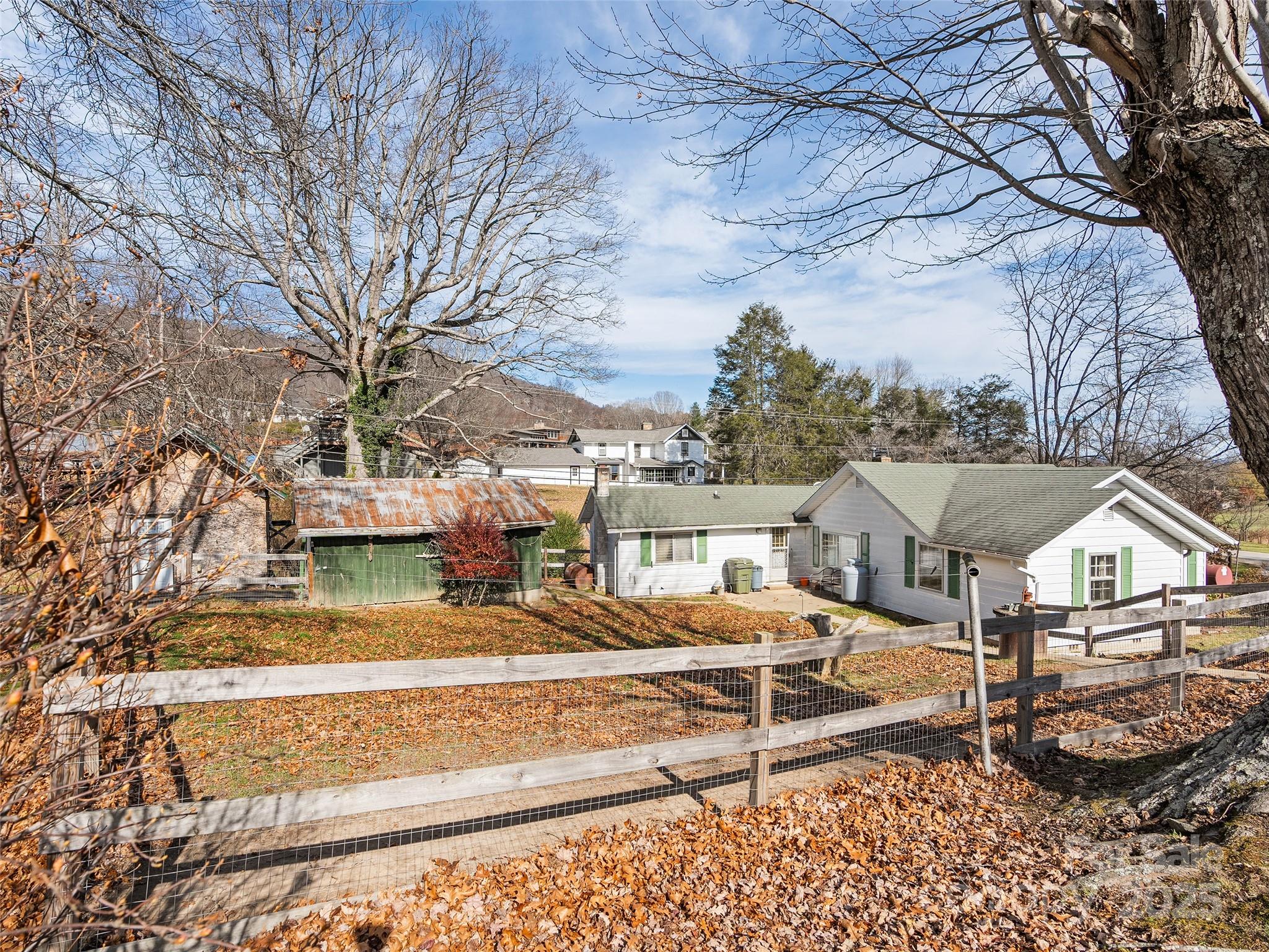 396 Will Hyatt Road Waynesville, NC 28786 - Photo 15 of 23 a view of a white house with a large tree and wooden fence