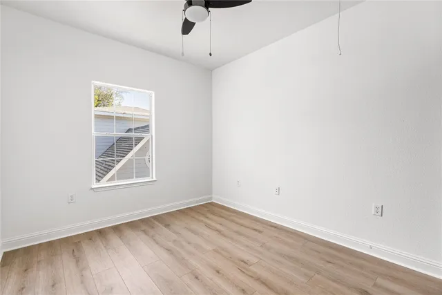 an empty room with a window and a ceiling fan