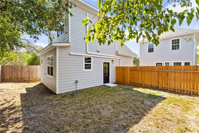 a view of a backyard with a tree and wooden fence