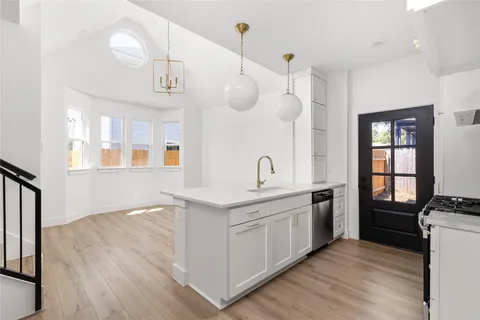 a kitchen with stainless steel appliances granite countertop a sink a stove a refrigerator and island with wooden floor