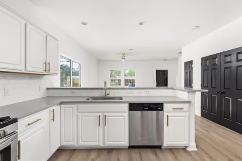 a kitchen with white cabinets and sink