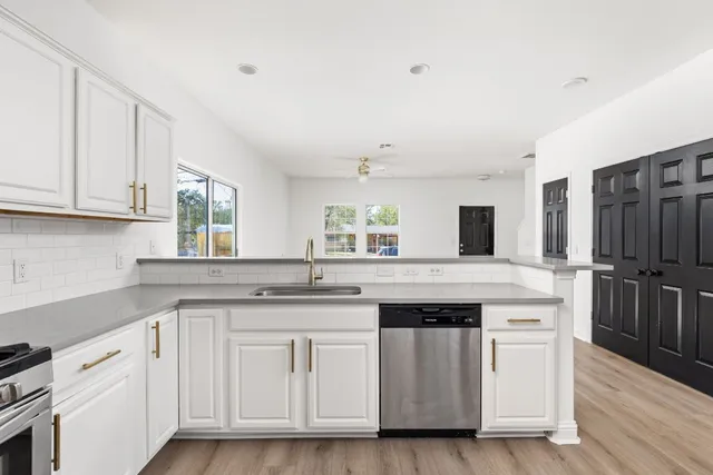 a kitchen with white cabinets and sink