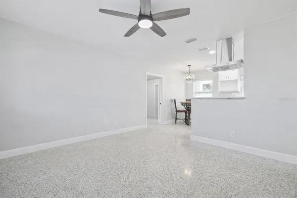 en empty room with chandelier fan and windows