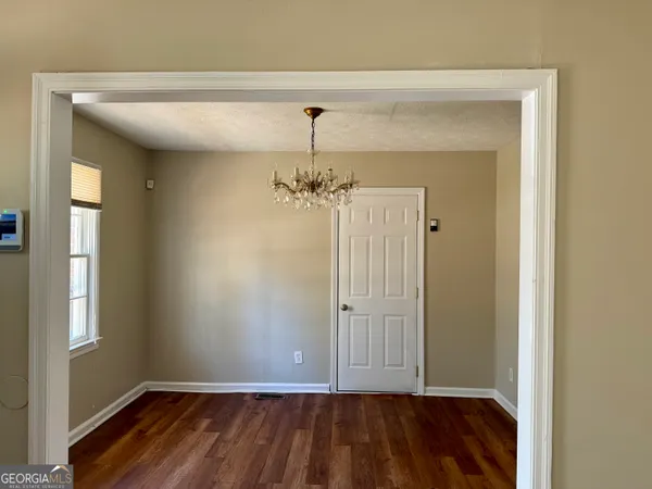 a view of a hallway with wooden floor and a bathroom