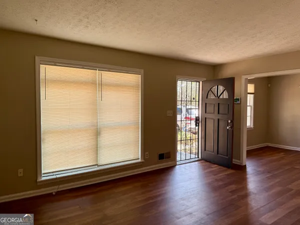 an empty room with wooden floor and windows