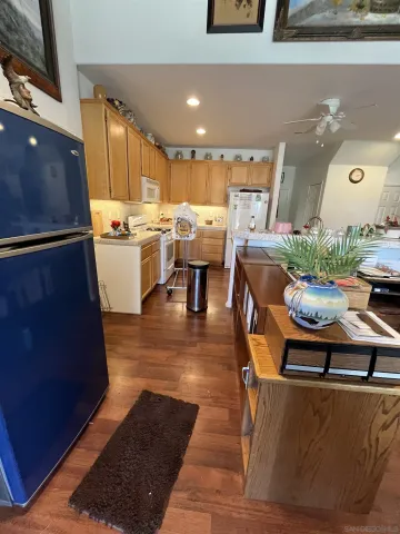 a kitchen with stainless steel appliances granite countertop a stove top oven a refrigerator a kitchen island and chairs with wooden floors