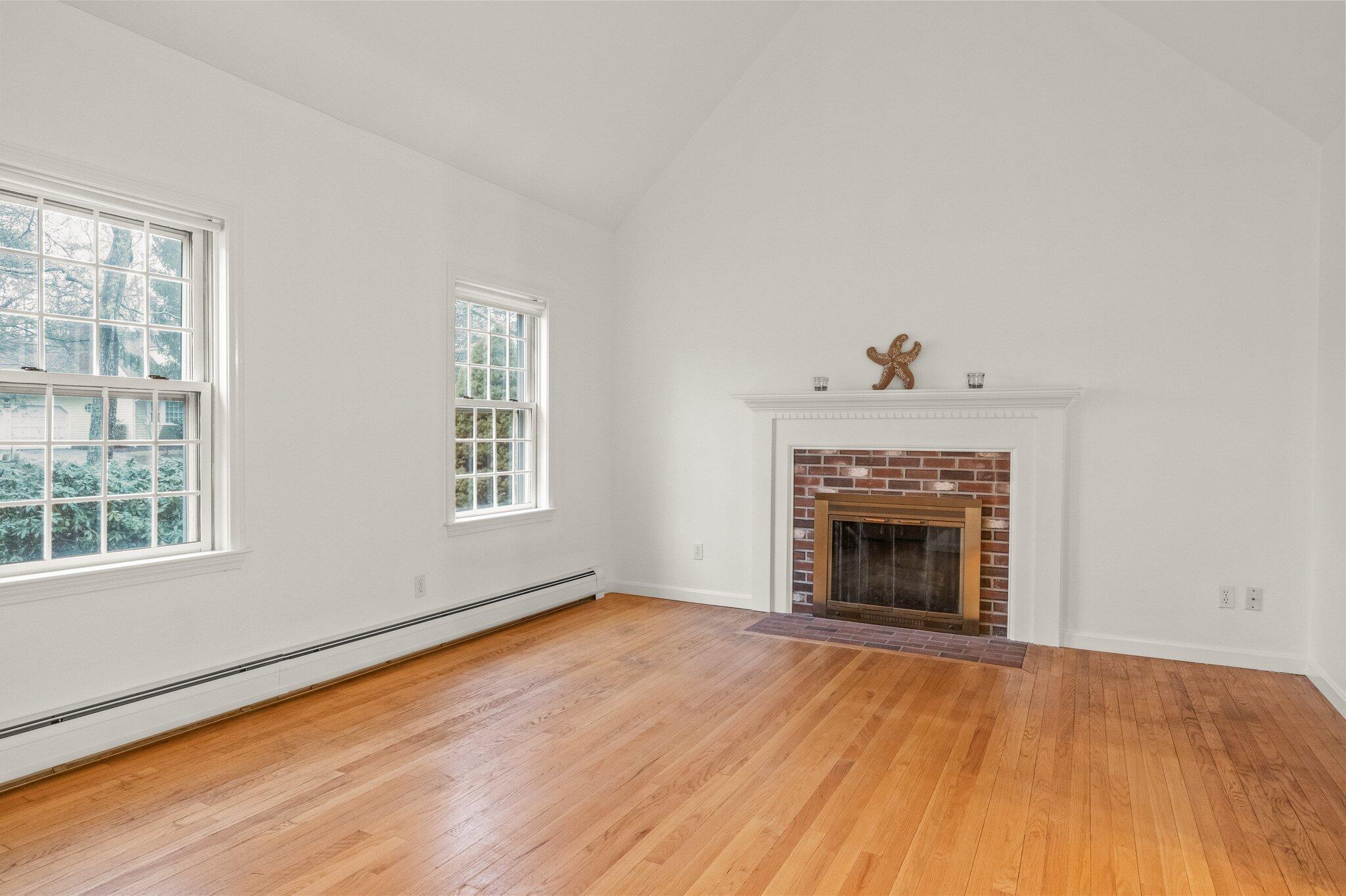 52 Goose Point Road Centerville, MA 02601 - Photo 9 of 71 an empty room with windows fireplace and wooden floor