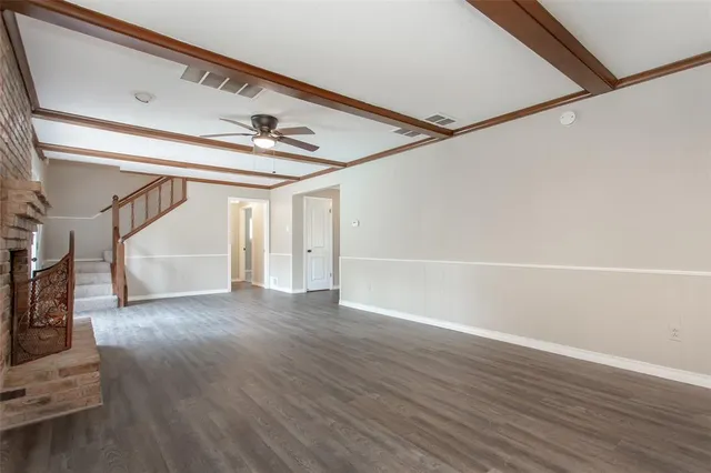 a view of an empty room with wooden floor and a ceiling fan
