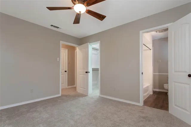 an empty room with closet and a chandelier fan