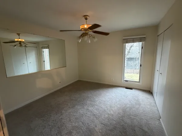 an empty room with windows and fan
