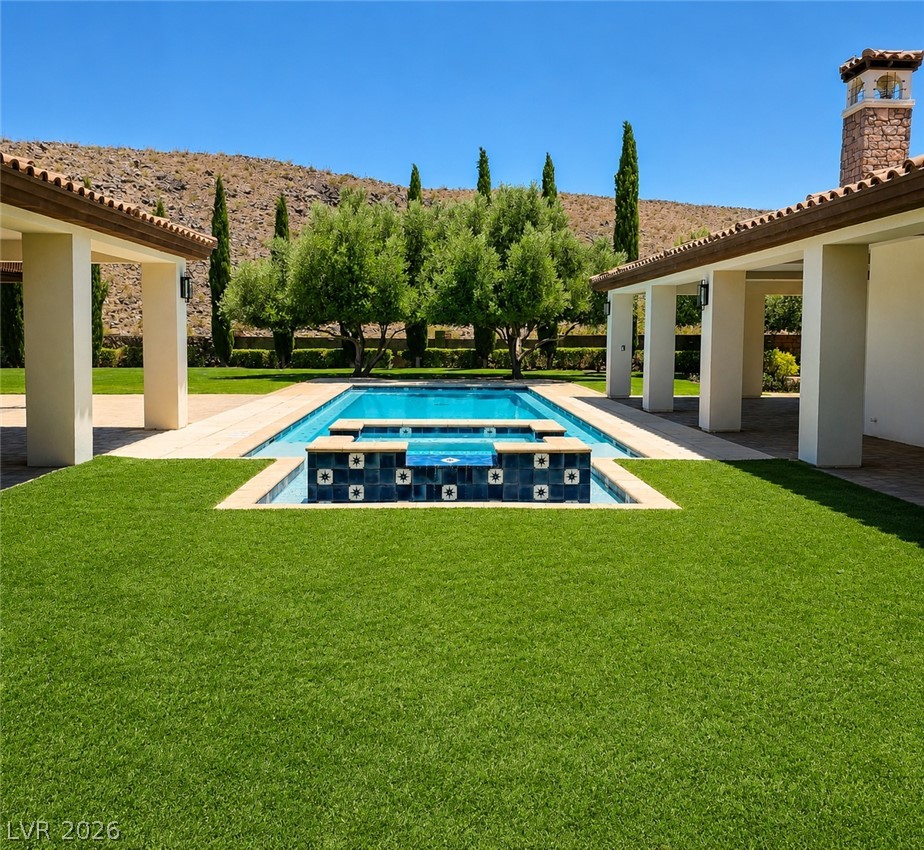 1140 Julie Road Henderson, NV 89002 - Photo 2 of 85 Your inviting backyard oasis features a fully remodeled 1100 sq ft shimmering pool with a raised spa, framed by verdant lawn, mature trees, mountain views and multiple covered patios. 1140 Julie Rd Henderson 89002