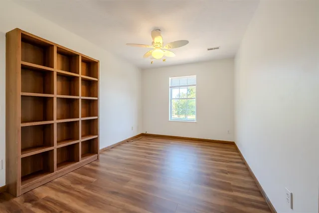 a view of an empty room with a window and wooden floor